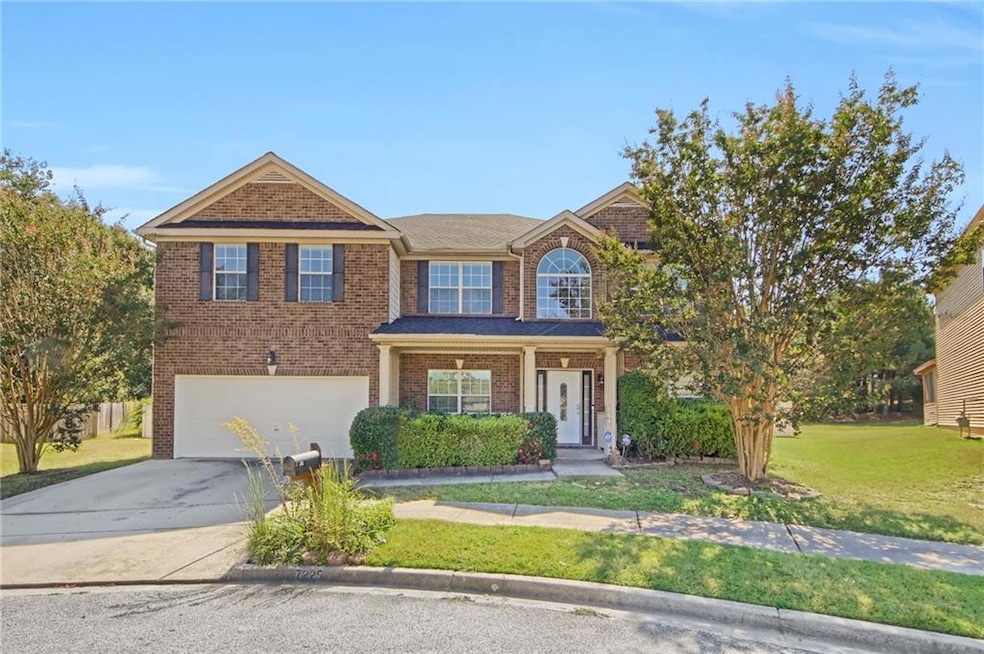 View of front of property featuring covered porch, concrete driveway, a front lawn, brick siding, and a garage