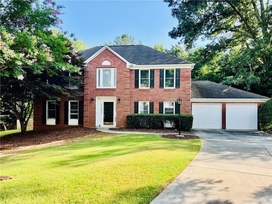 Colonial house featuring driveway, a front lawn, brick siding, an attached garage, and a shingled roof