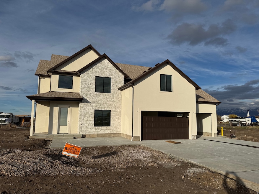 View of front facade with stone siding, a shingled roof, driveway, an attached garage, and stucco siding