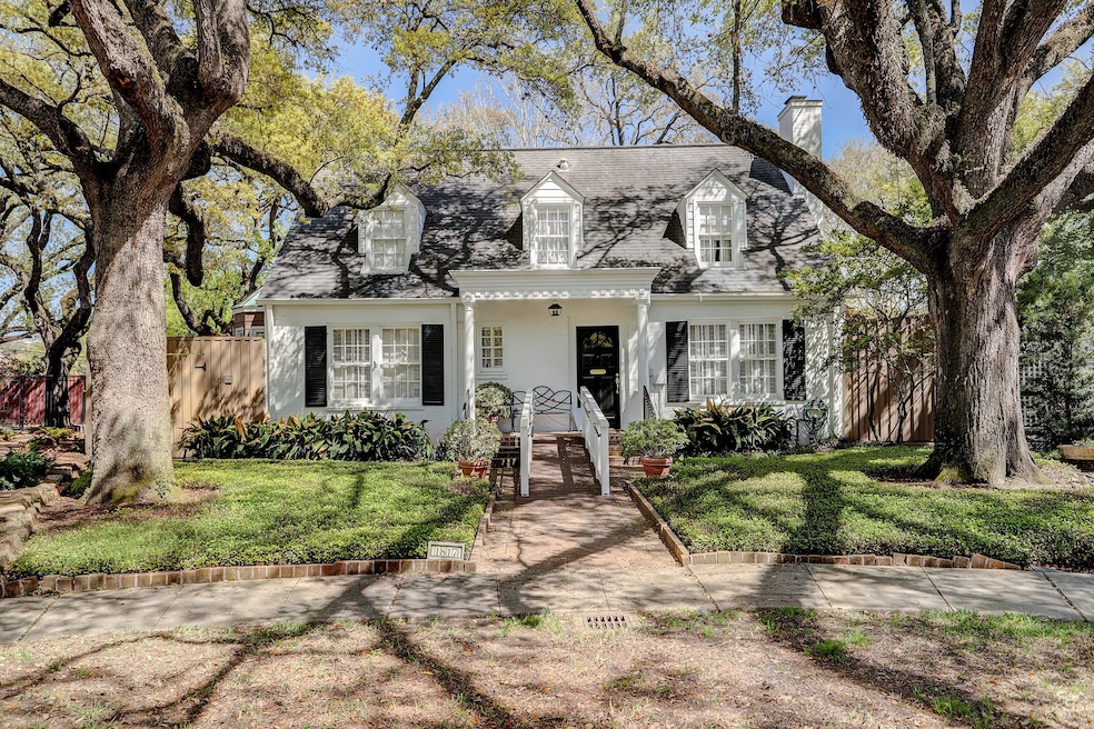 Front elevation of 1817 Sharp Place in River Oaks with brick facade and flanked by beautiful oak trees. Courtyard setting!