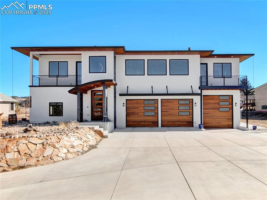 Modern home with a garage, a balcony, driveway, and stucco siding