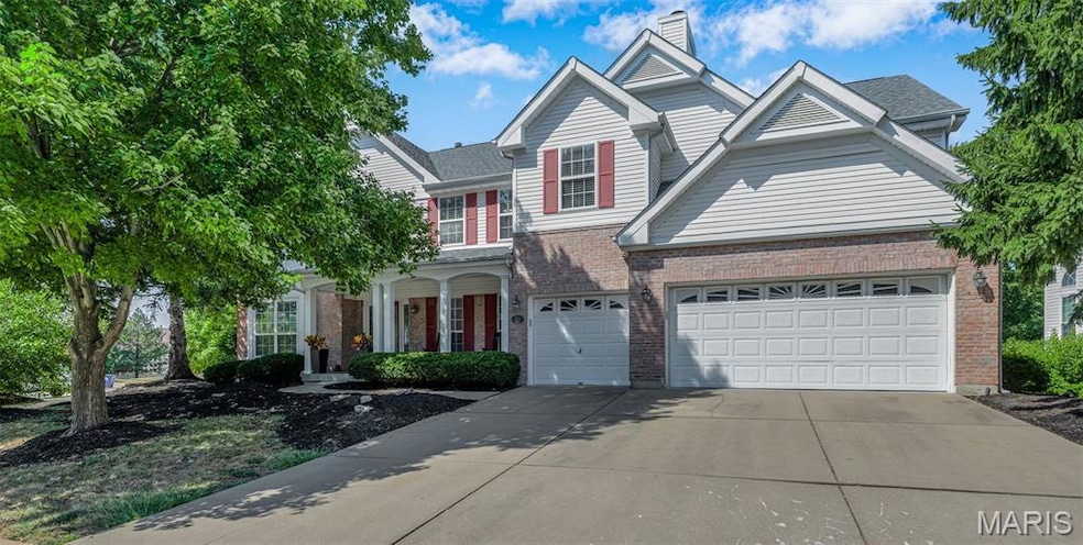 Traditional-style home featuring driveway, a garage, a chimney, and brick siding