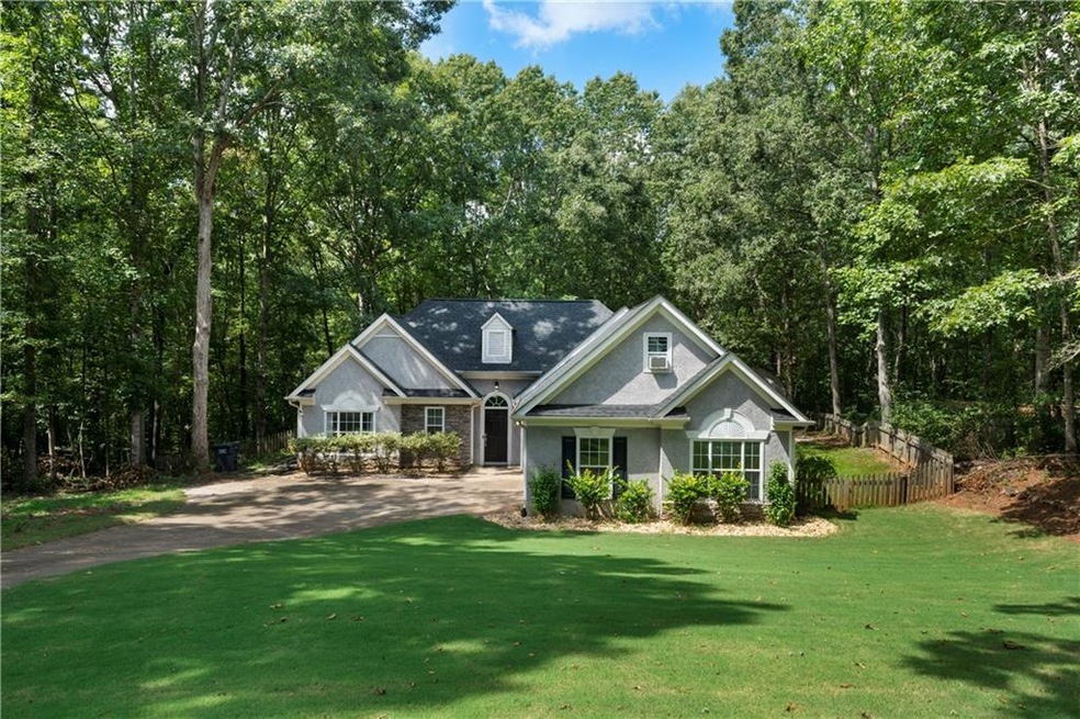 View of front of property featuring a view of trees and stucco siding