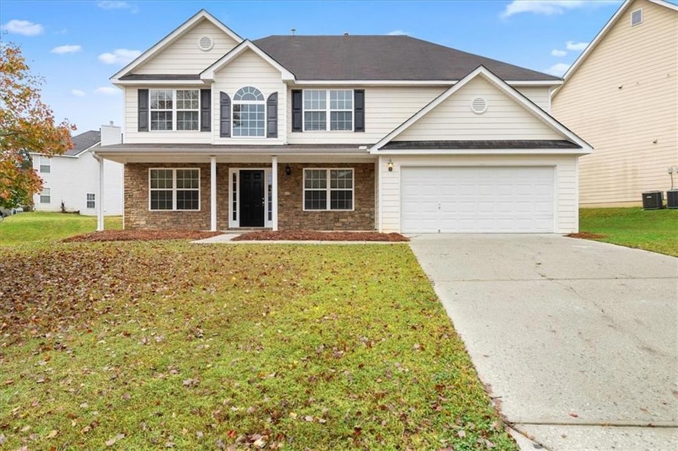 Traditional-style house with concrete driveway, a porch, stone siding, a garage, and a front lawn