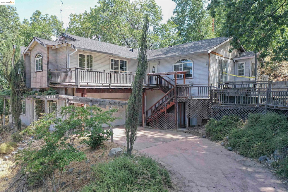 View of front of home featuring a wooden deck, concrete driveway, stairway, a garage, and roof with shingles