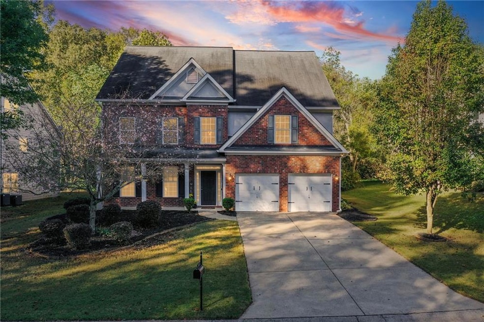 Traditional-style house with brick siding, driveway, a lawn, and a garage