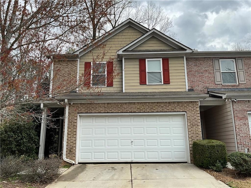 View of front of house with an attached garage, brick siding, and driveway