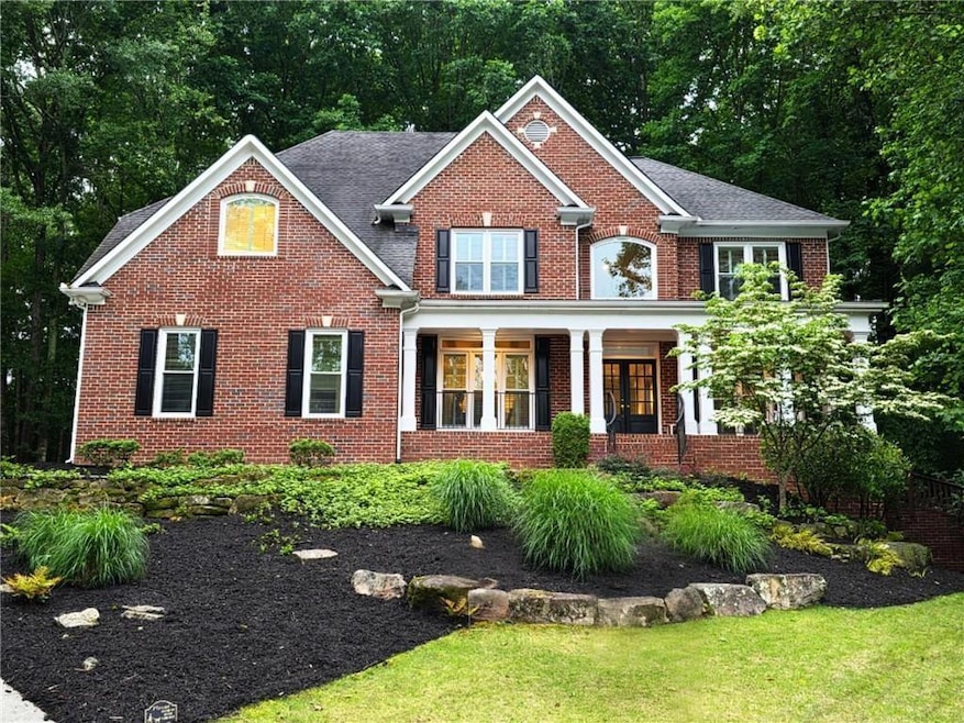 View of front of property with brick siding, a front lawn, and a porch