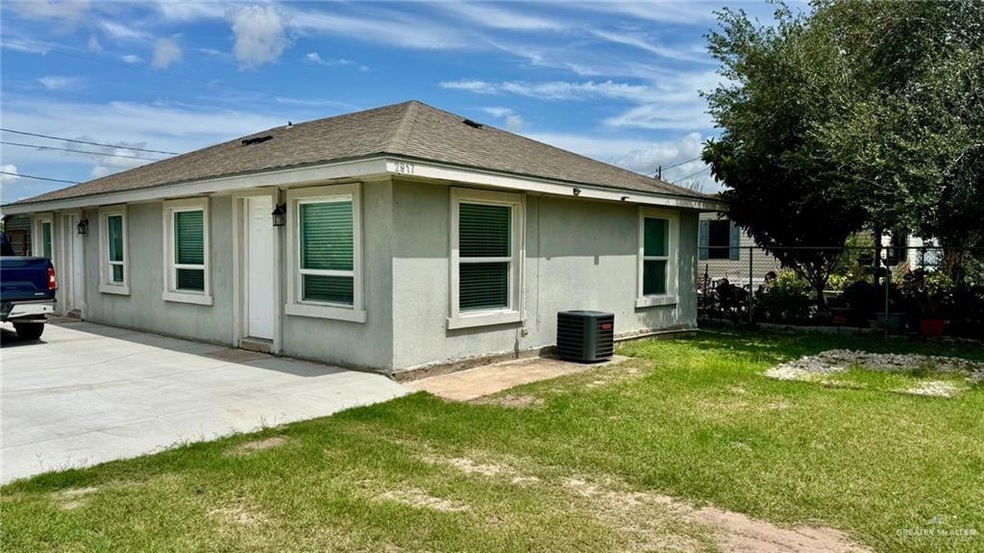 Rear view of property featuring central AC unit, stucco siding, a patio, and roof with shingles