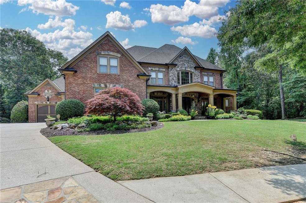 View of front of home with brick siding, a front lawn, stone siding, and a garage