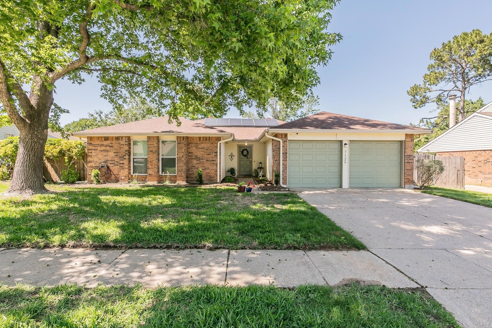Single story home with a garage, solar panels, and a front yard
