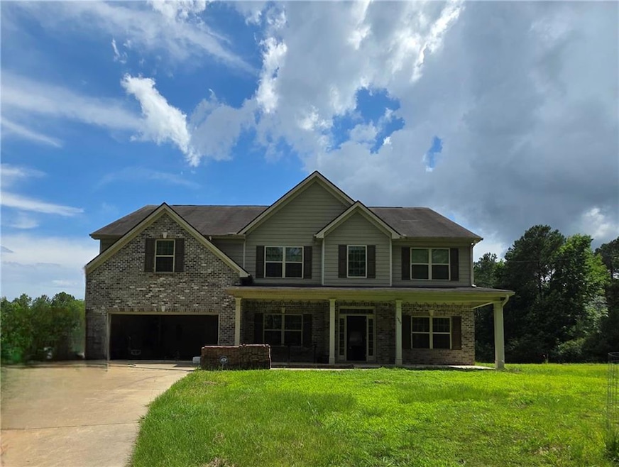 View of front of property with covered porch, concrete driveway, an attached garage, a front yard, and brick siding