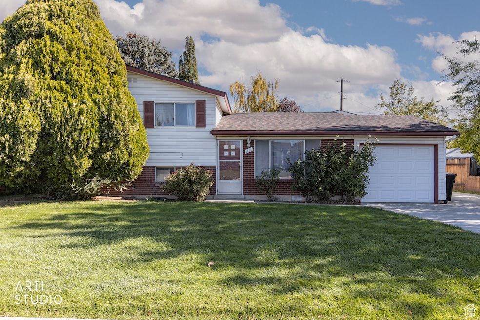 Tri-level home with a front yard, a garage, brick siding, and driveway