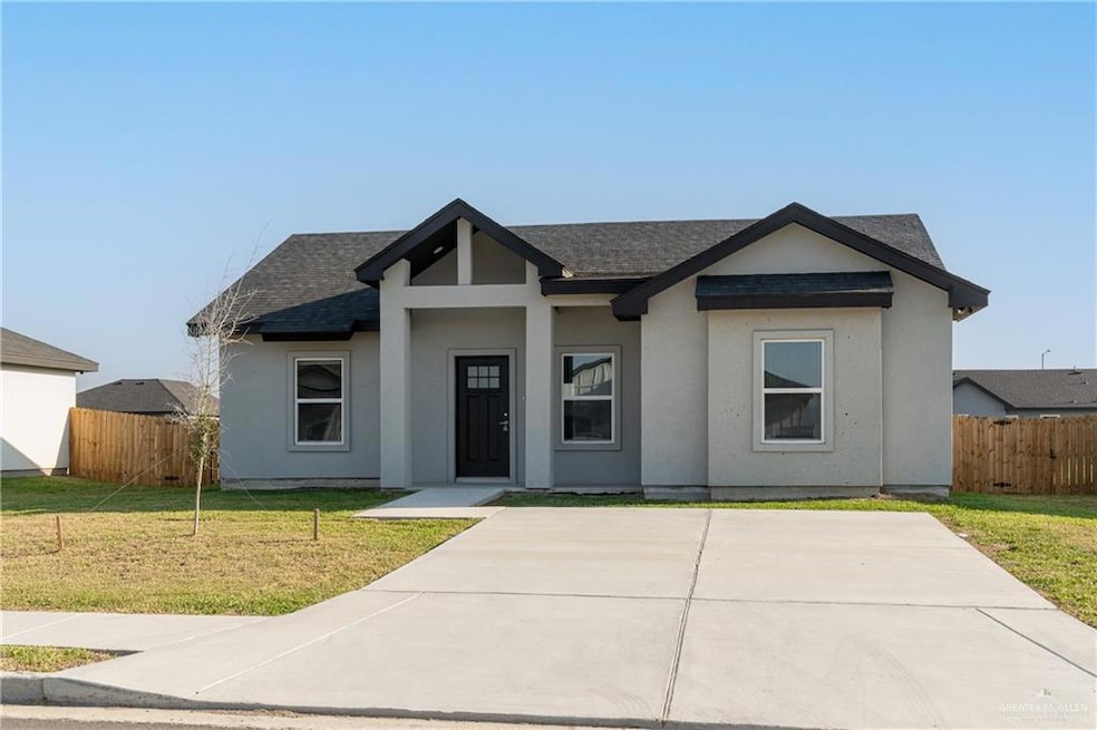 View of front of property with stucco siding, roof with shingles, a front lawn, and fence