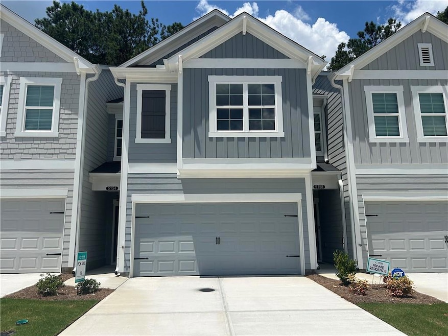 View of front of house featuring board and batten siding, driveway, and a garage