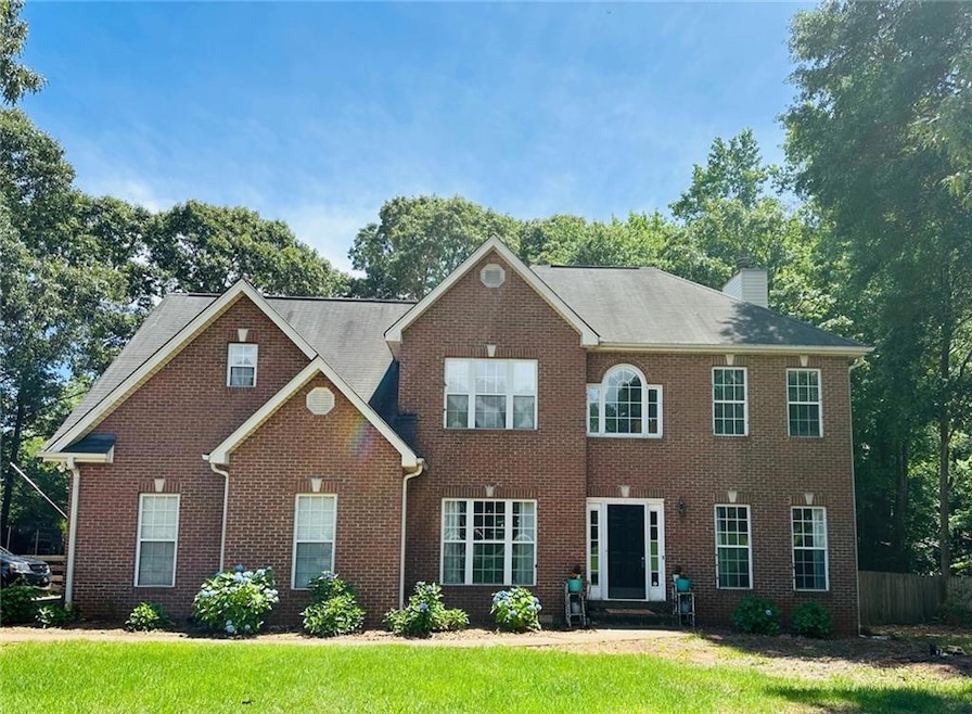 Colonial inspired home with brick siding, a chimney, and a front yard