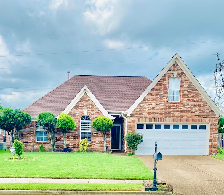 Traditional home with roof with shingles, driveway, a front yard, and brick siding