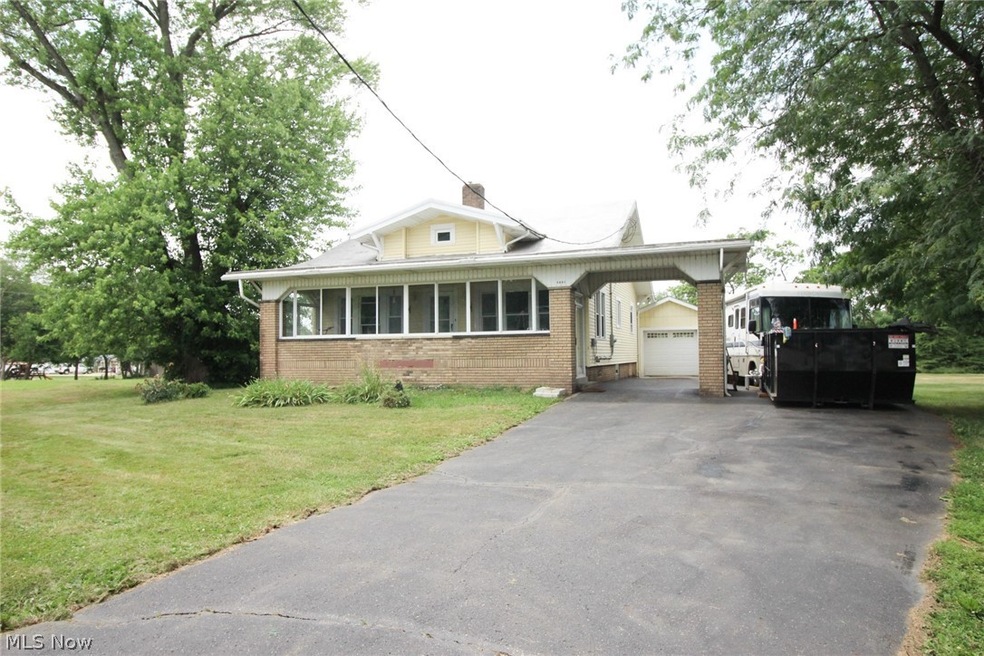 View of front of property featuring a garage, an outbuilding, a carport, and a front lawn