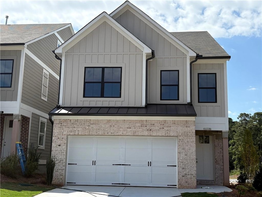 View of front of property with board and batten siding, an attached garage, brick siding, and concrete driveway