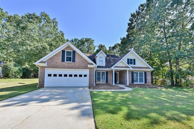 Level lot with long driveway and lush green lawn.
