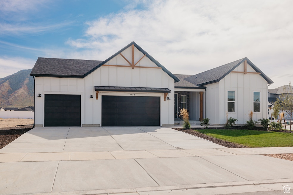 Modern farmhouse featuring board and batten siding, a shingled roof, concrete driveway, an attached garage, and a standing seam roof