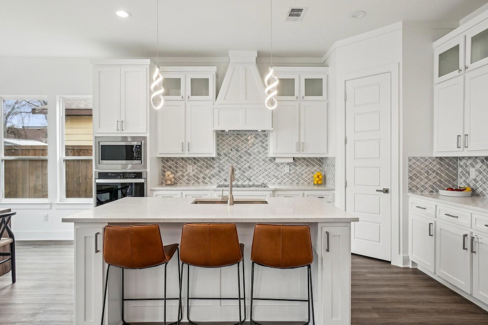 Kitchen with pendant lighting, white cabinetry, st