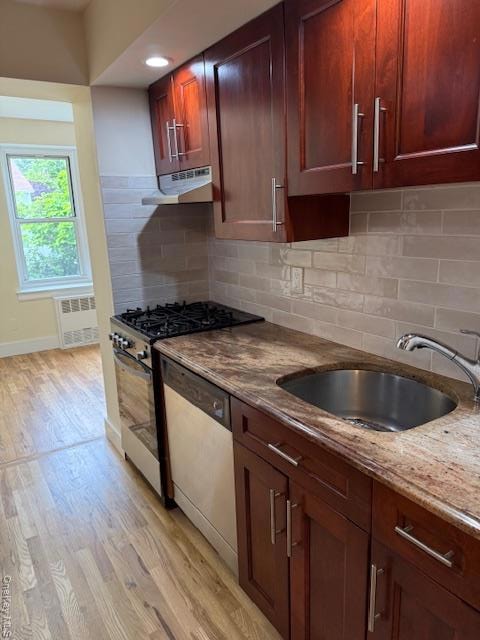 Kitchen featuring range, light stone countertops, light wood finished floors, dishwashing machine, and ventilation hood