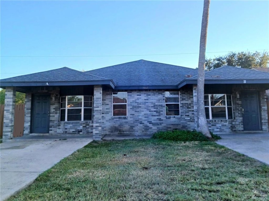 Brick home with roof shingles, a front lawn, a porch, and brick siding