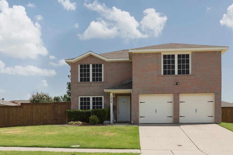Traditional-style home featuring brick siding, fence, concrete driveway, a front yard, and a garage