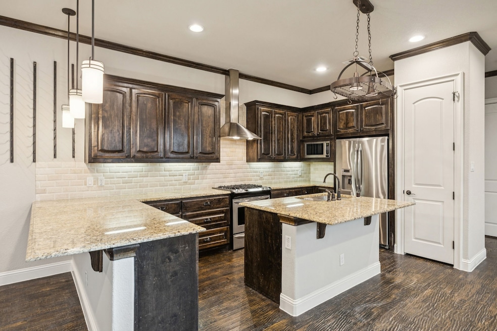 Kitchen with a breakfast bar area, dark brown cabinetry, decorative backsplash, light stone countertops, and crown molding
