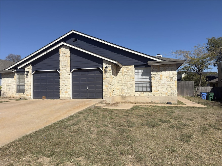 View of front of house with stone siding, driveway, and a garage