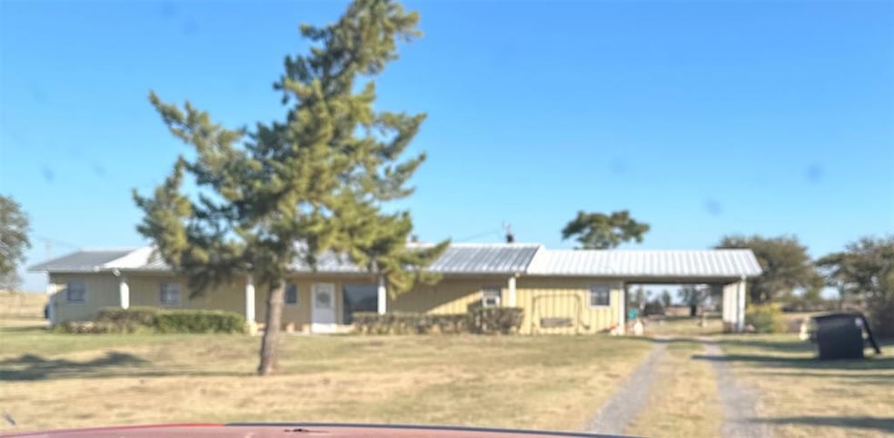 View of front of house with dirt driveway and a front lawn