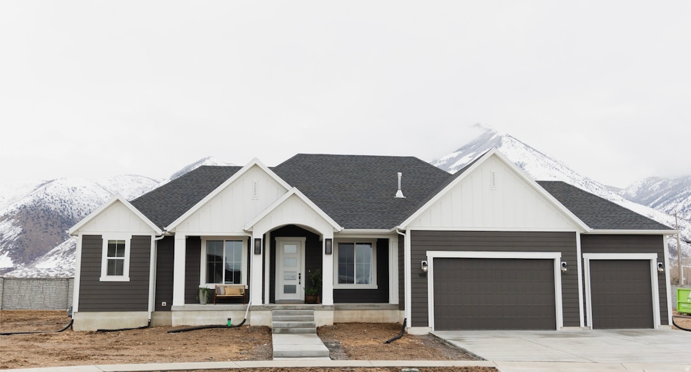 View of front of property featuring a mountain view, a garage, concrete driveway, and a shingled roof