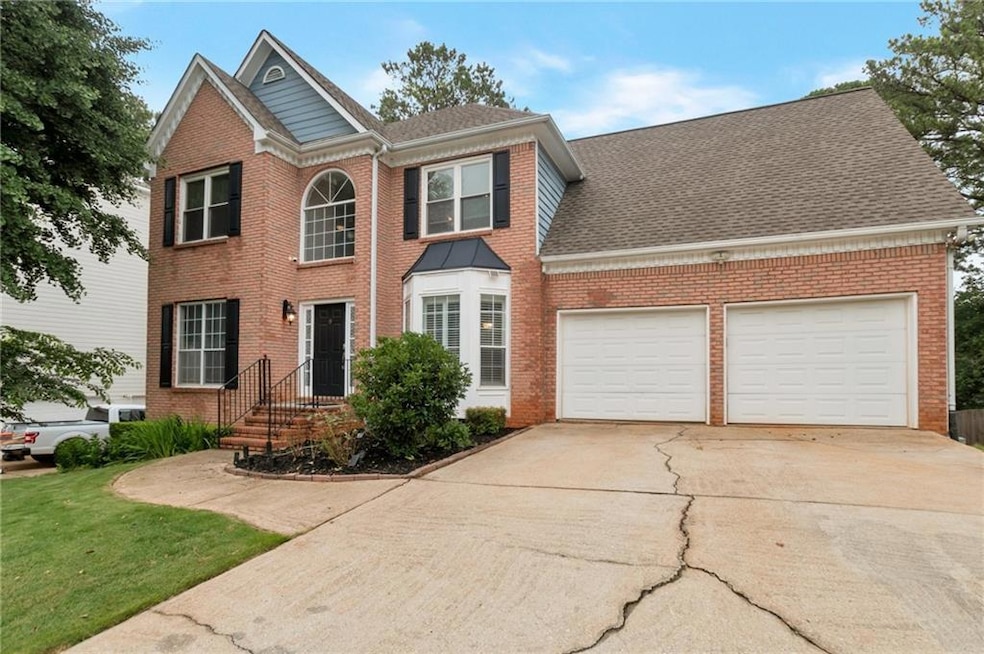 Colonial inspired home with brick siding, driveway, a garage, and a front lawn
