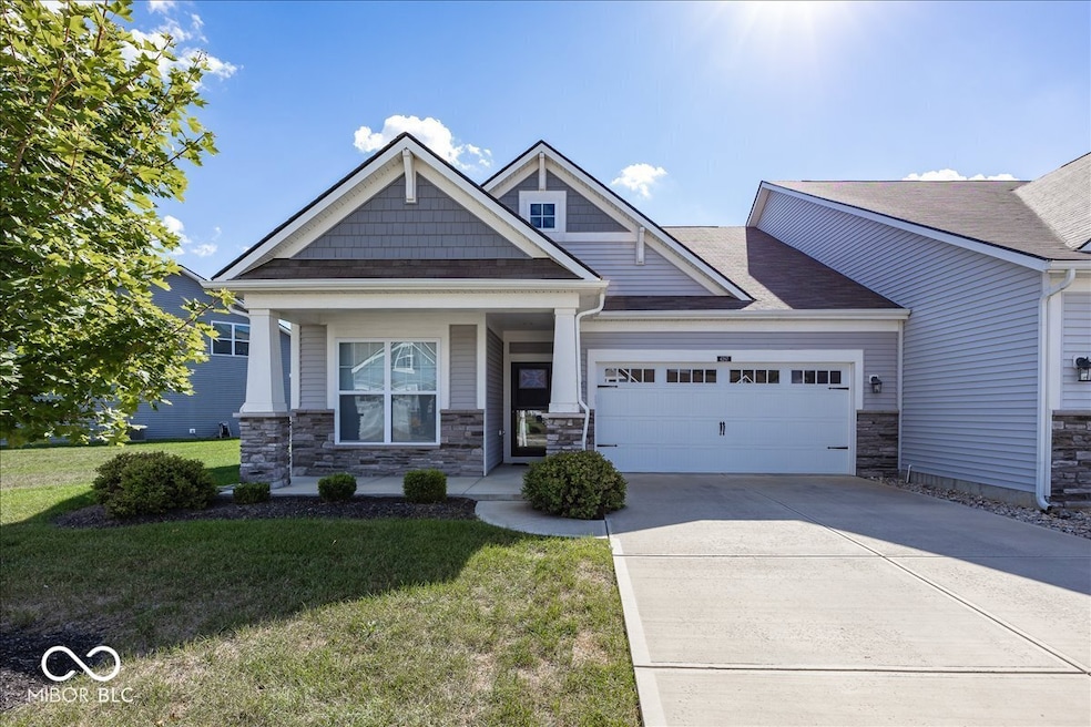 Craftsman style condo featuring  large open porch stone siding, a front yard, a garage, concrete driveway, and covered porch
