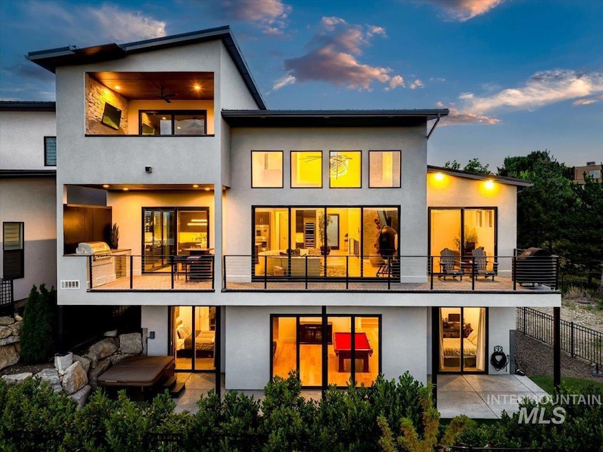 Back of property at dusk with a balcony, a patio, and stucco siding