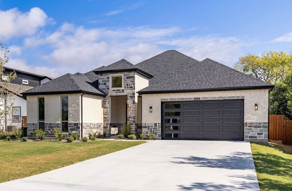French country home with stone siding, concrete driveway, roof with shingles, a garage, and brick siding