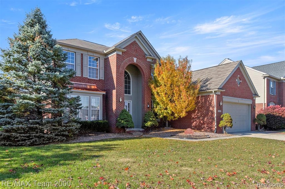 Traditional-style house featuring brick siding, a front lawn, a garage, and concrete driveway