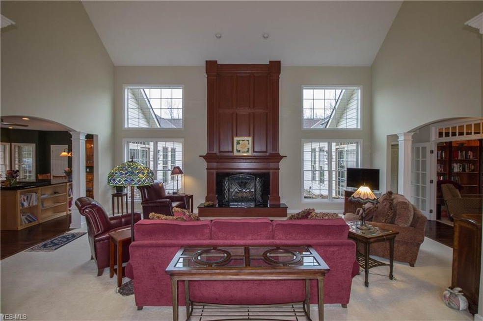 Soaring cherry fireplace surround flanked by windows with courtyard view lends to beautiful entertaining or relaxing space.
