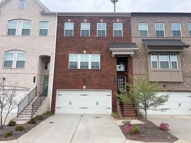 View of property featuring concrete driveway, bric