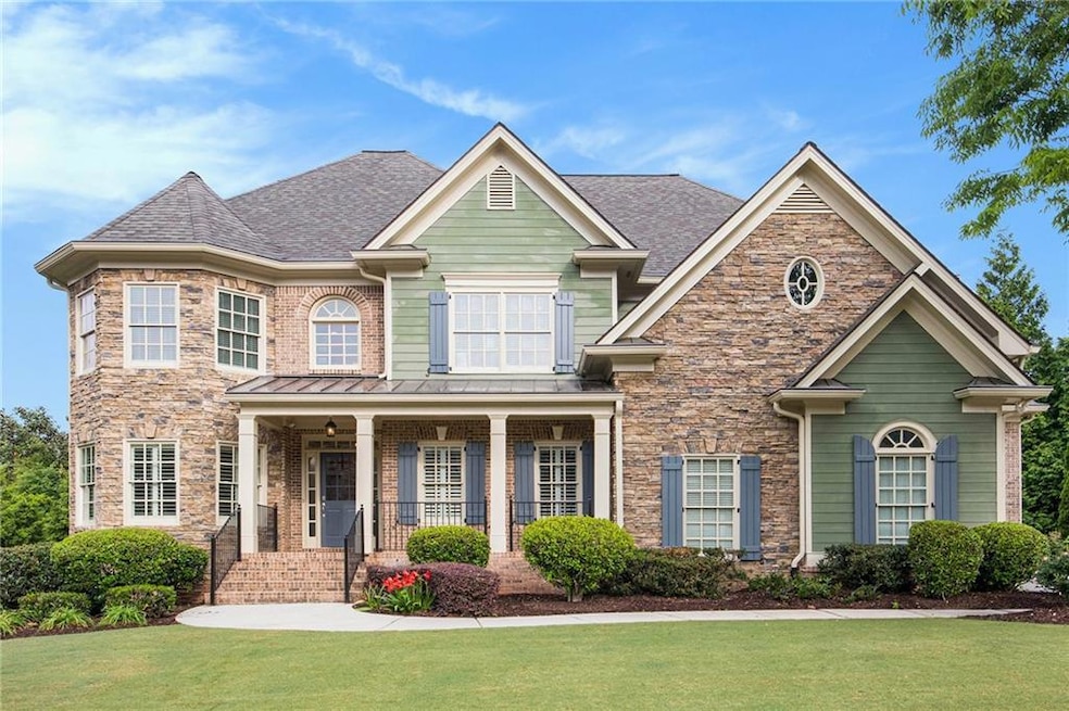View of front of house with a front lawn, a shingled roof, stone siding, a porch, and a standing seam roof
