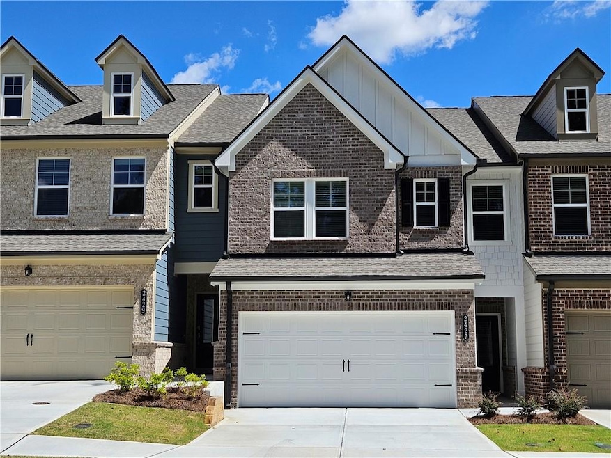 View of property featuring brick siding, driveway, and an attached garage