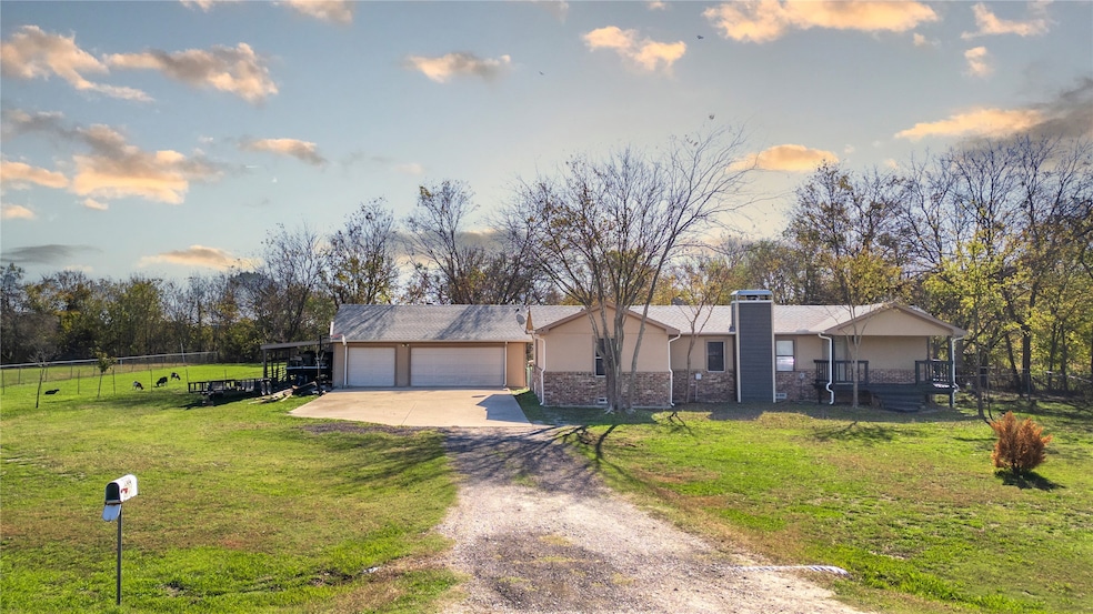 View of front facade with stucco siding, concrete driveway, a front yard, and fence