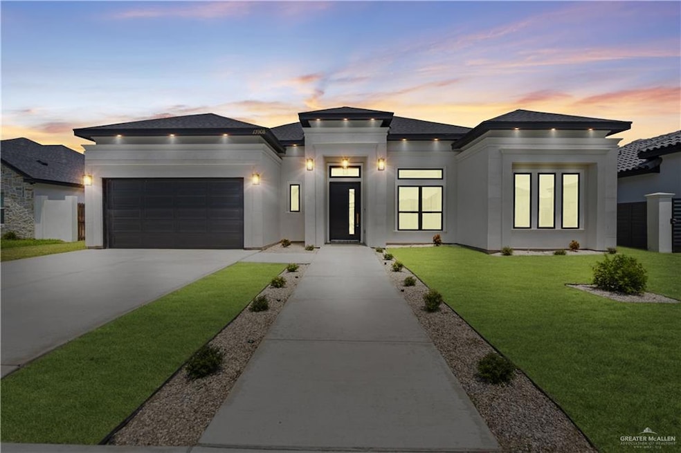 Prairie-style home featuring a garage, driveway, a front lawn, stucco siding, and a shingled roof