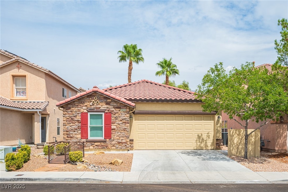 Mediterranean / spanish-style house featuring a tiled roof, driveway, stucco siding, an attached garage, and stone siding