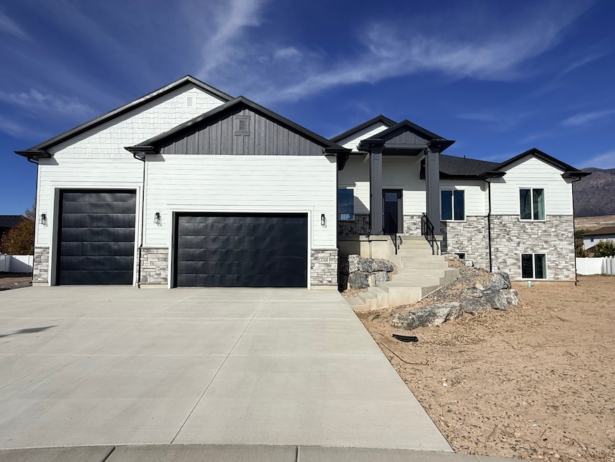 View of front of property featuring stone siding, a garage, a porch, driveway, and board and batten siding