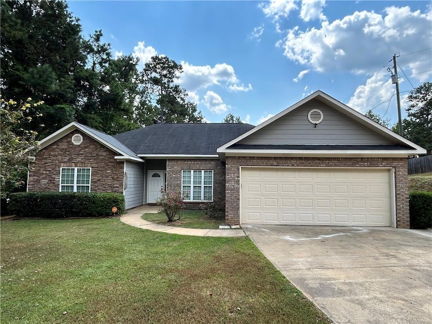 Ranch-style house with a front yard, driveway, a garage, and brick siding
