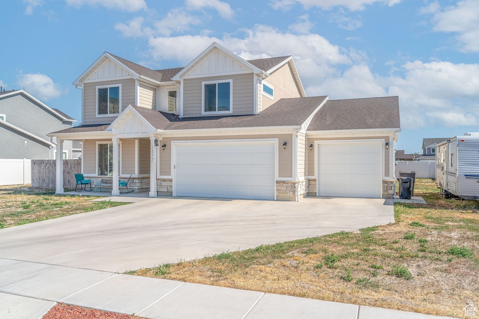Craftsman house featuring board and batten siding, covered porch, stone siding, driveway, and a shingled roof