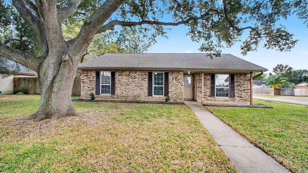 A beautiful front view of the home featuring a large, mature shade tree, fresh landscaping, and a welcoming walkway leading to the covered front porch. A perfect first impression with great curb appeal.