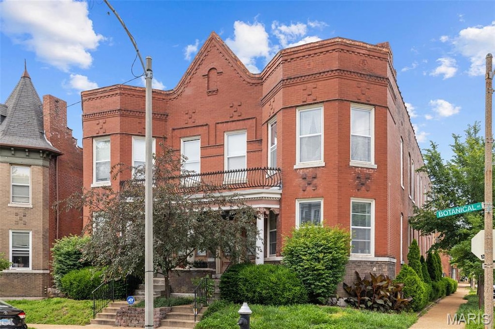 View of front of house with a balcony and brick siding